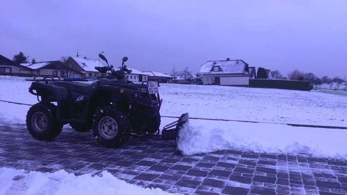 Ein Geländefahrzeug mit montiertem Schneepflug steht im Schnee.