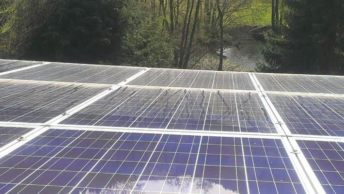 Eine Reihe von Solarmodulen auf einem Dach mit Bäumen im Hintergrund