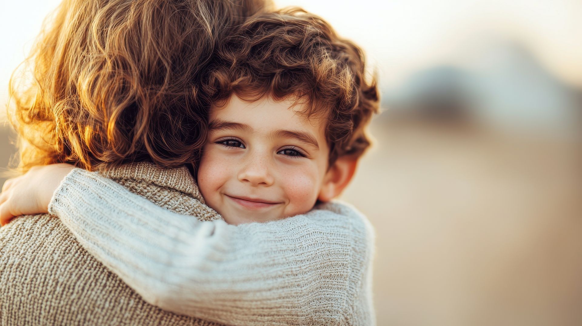Enfant souriant enlaçant sa maman.