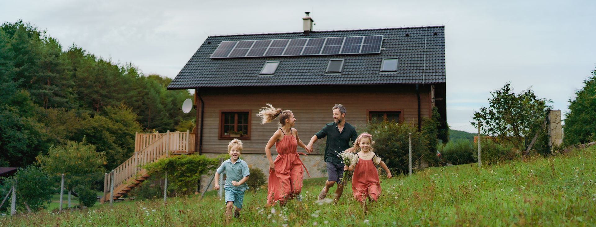 Une famille se promène dans une cour herbeuse à côté d'une maison équipée de panneaux solaires.