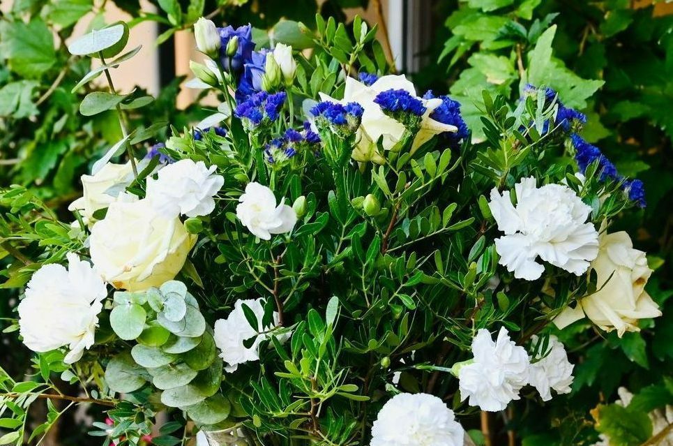 Fleurs blanches et bleues dans un arrangement floral dense et luxuriant.