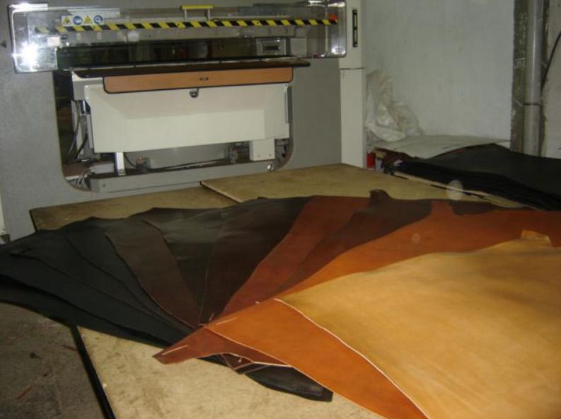 Varias piezas de cuero están colocadas sobre una mesa delante de una máquina.