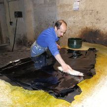 Un hombre está limpiando un trozo de cuero con un paño.