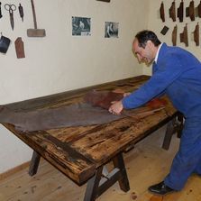 Un hombre está trabajando en un trozo de cuero sobre una mesa de madera.