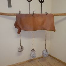 Un trozo de cuero cuelga de unos ganchos en una pared.
