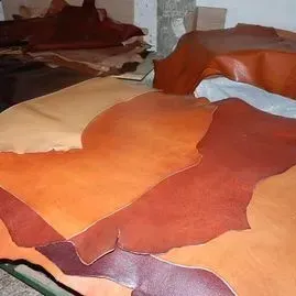 Montón de trozos de piel de cuero marrón rojizo sobre una mesa en un taller.