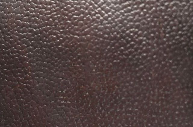 Primer plano de una superficie de cuero texturizado de color marrón oscuro.