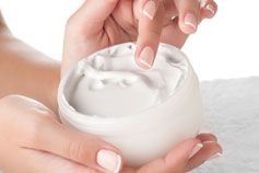 Una mujer sostiene un tarro de crema en sus manos.