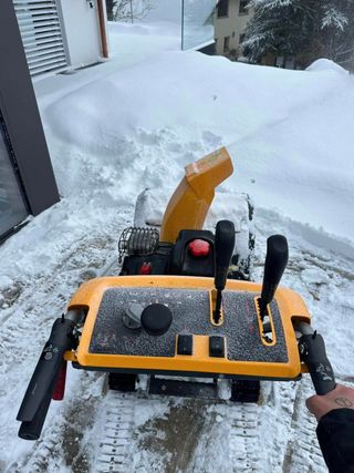 Une personne tient une souffleuse à neige jaune dans la neige | André & Jardin