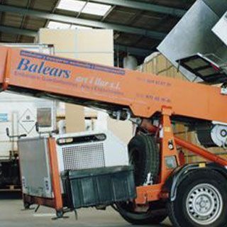 Un gran camión balear de color naranja está estacionado en un almacén.
