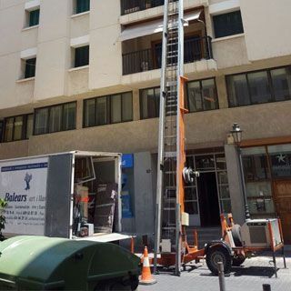 Un camión de mudanzas con una escalera adjunta está estacionado frente a un edificio.