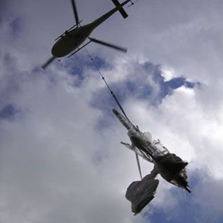 Dos helicópteros vuelan en el cielo transportando un objeto de gran tamaño.