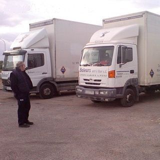 Dos camiones blancos están estacionados uno al lado del otro en un estacionamiento.