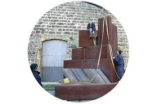 Un grupo de personas está trabajando en una escultura frente a un edificio de ladrillos.