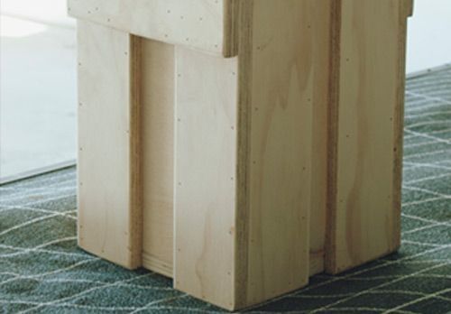 Un taburete de madera está sentado sobre una alfombra en el suelo.