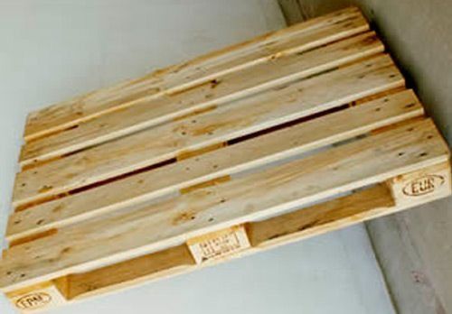 Una paleta de madera reposa sobre una pared blanca.