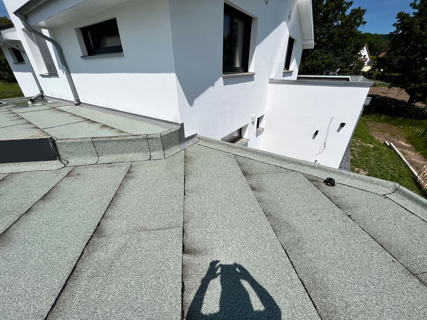 Ein weißes Haus mit einem roten Dach hat eine Satellitenschüssel an der Seite