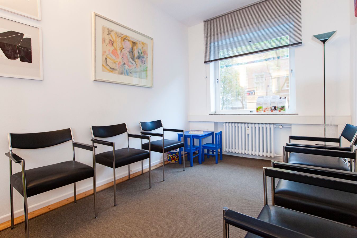 Moderner Konferenzraum mit langem Holztisch, Bücherregalen und blauem Teppich vor großen Fenstern