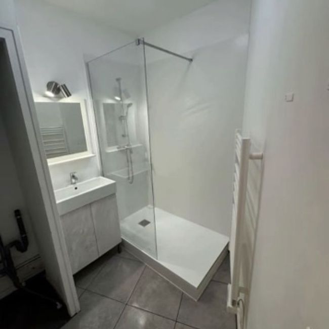 Salle de bains moderne avec meuble vasque blanc, cabine de douche en verre et sol carrelé gris