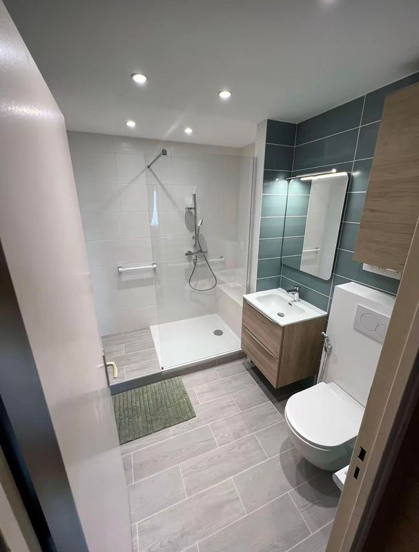 Salle de bains moderne avec douche à l’italienne, toilettes, meuble vasque et carrelage gris au sol