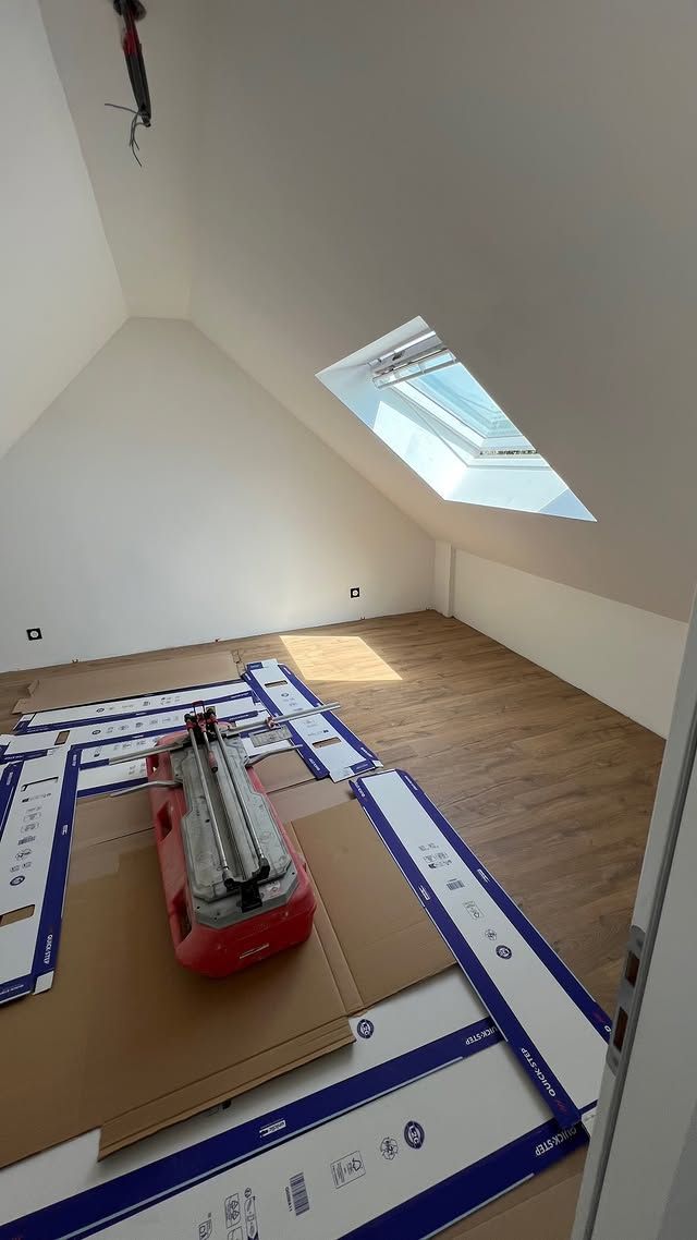 Combles partiellement aménagés, avec plafond mansardé, fenêtre de toit et matériaux de revêtement de sol disposés au sol