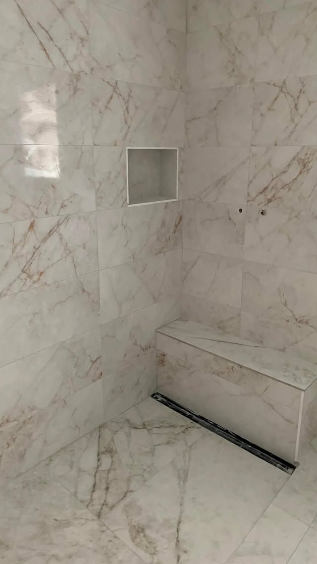Douche de salle de bains carrelée de marbre, avec banc intégré et petite niche murale