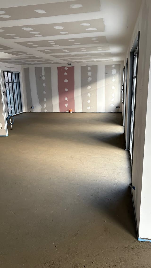 Pièce vide et inachevée avec moquette, cloisons sèches rayées et plafond irrégulier