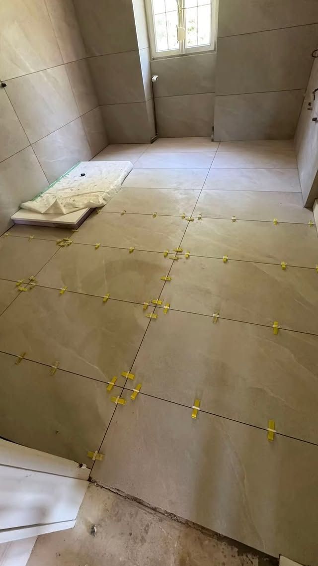 Grande pièce inachevée avec des dalles de sol en mousse beige et un tapis plié dans un coin.