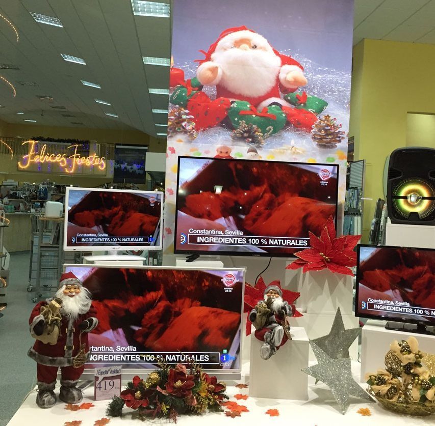 Exhibición de tienda con temática navideña con televisores que muestran contenido rojo; incluye decoraciones de Papá Noel y decoración festiva.