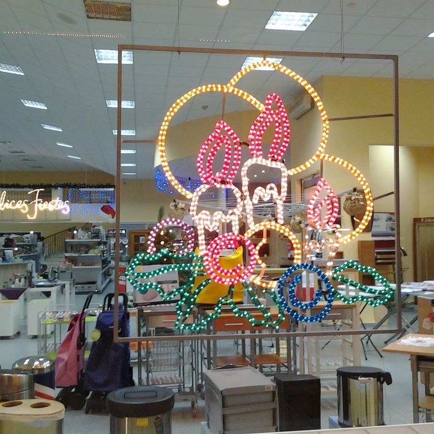 Exhibición de luces navideñas en una tienda, con círculos y formas iluminadas de colores dentro de un marco cuadrado.