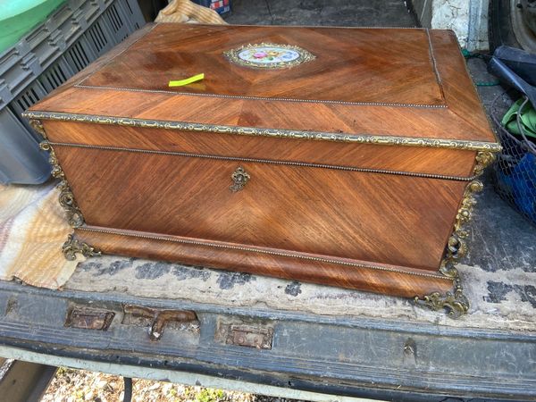 Coffre ancien en bois avec garnitures en laiton, placage à grain diagonal et incrustation florale centrale en porcelaine sur le couvercle.