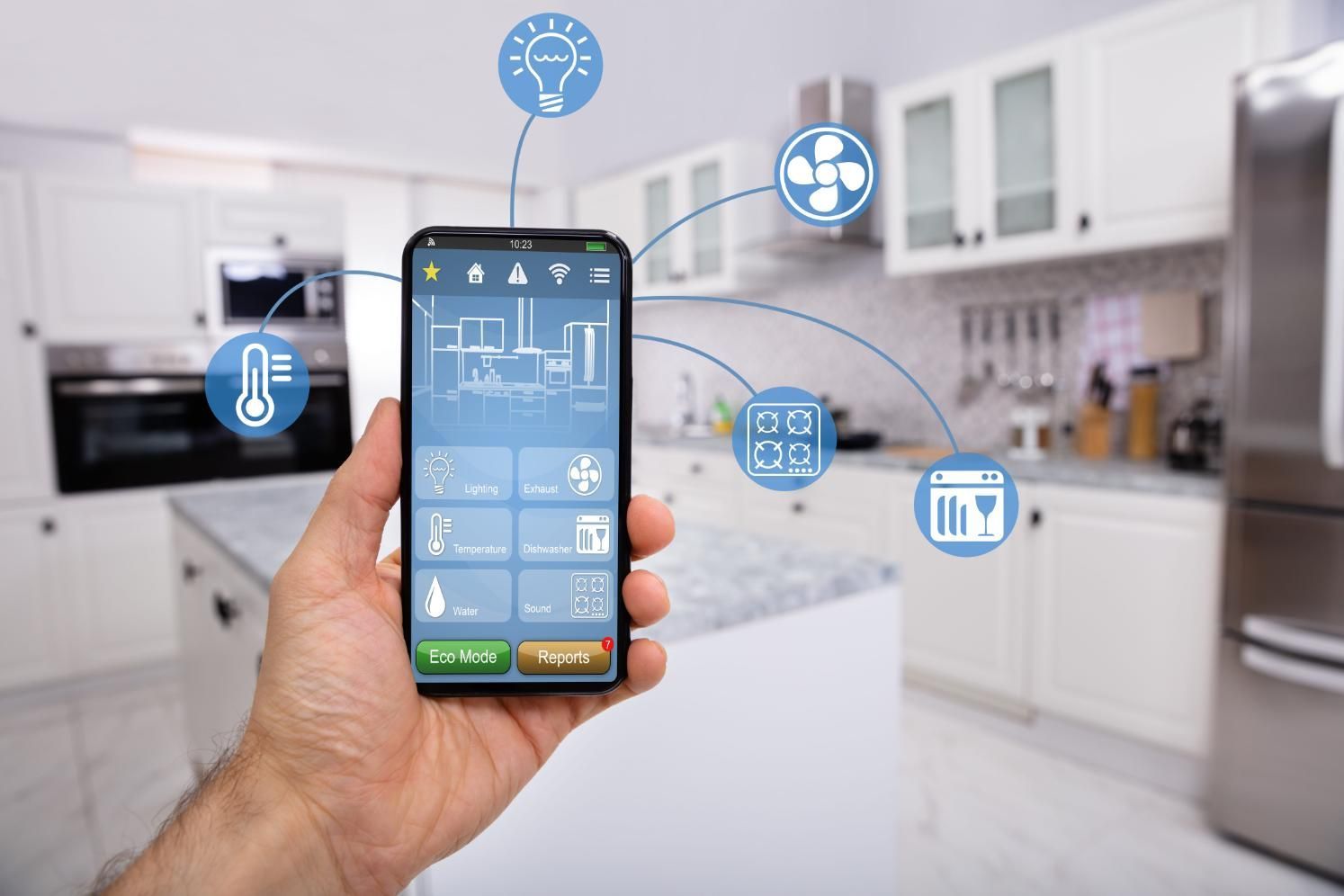 Una mano sostiene un teléfono inteligente con una aplicación de control para el hogar inteligente en una cocina moderna.