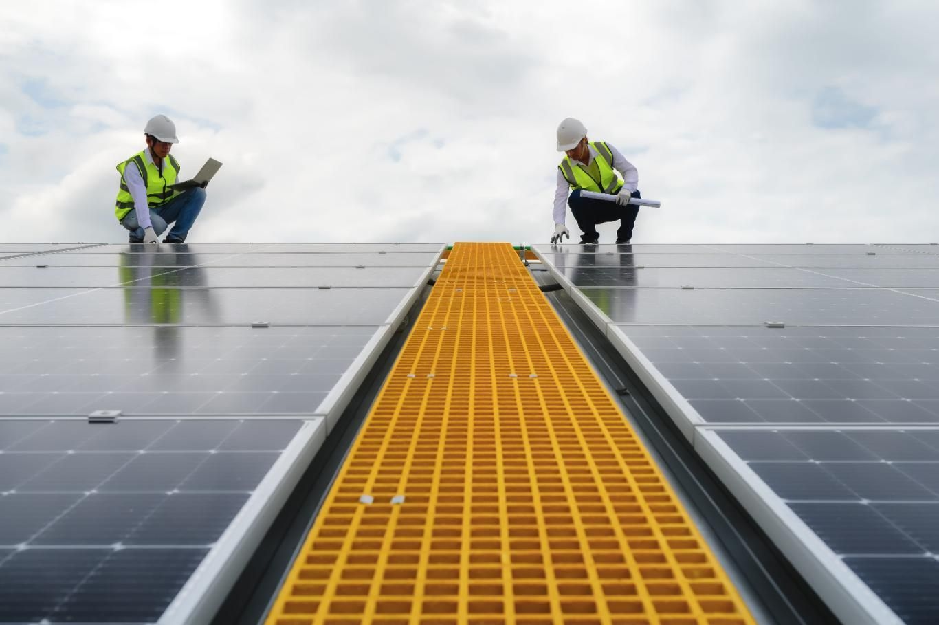 Trabajadores inspeccionando paneles solares en una pasarela en la azotea.