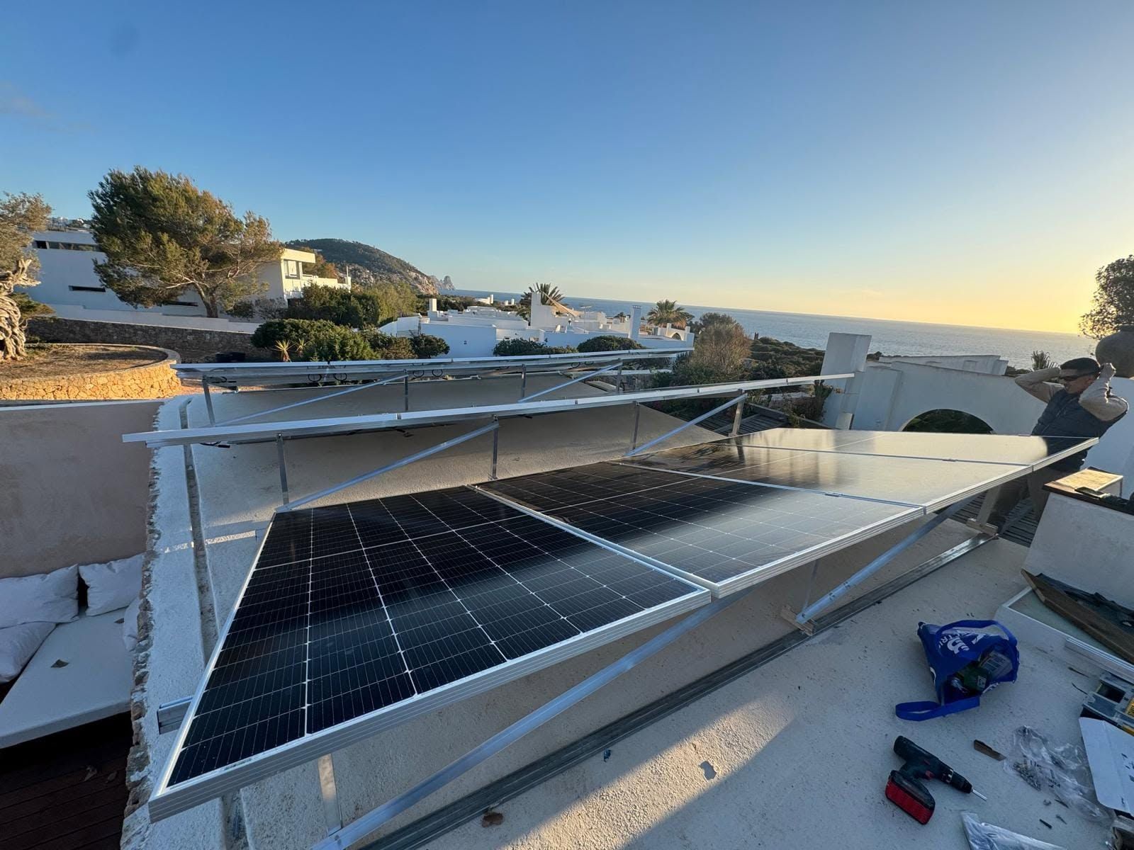 Paneles solares instalados en un tejado al atardecer, con herramientas y materiales cerca.
