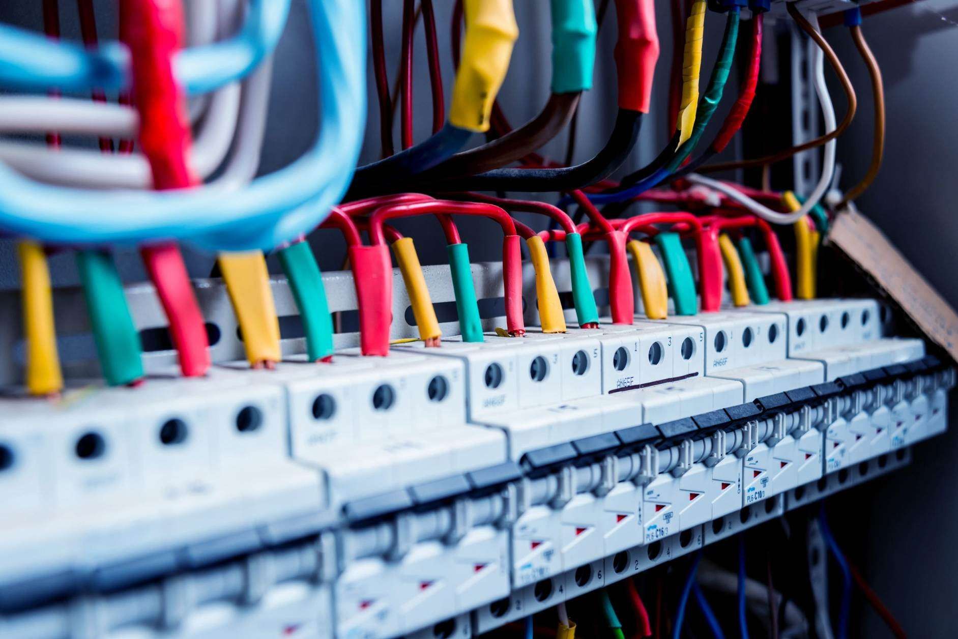 Panel eléctrico con filas de disyuntores y cableado de colores dentro de un armario de control.