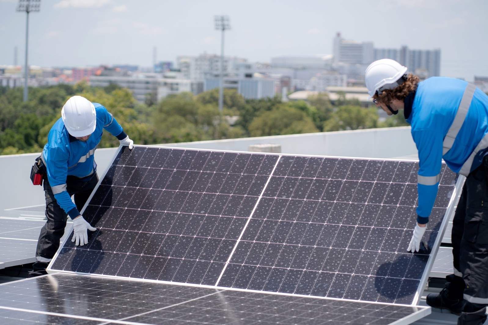 Dos trabajadores instalando paneles solares en un tejado bajo la luz del día.