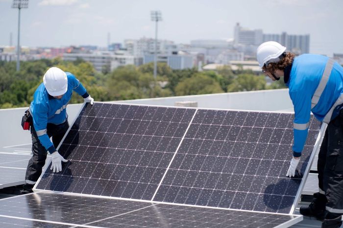 Dos trabajadores instalando paneles solares en un tejado bajo la luz del día.