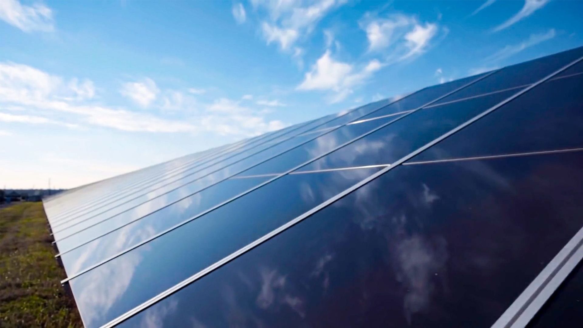 Hileras de paneles solares reflectantes bajo un cielo azul brillante.