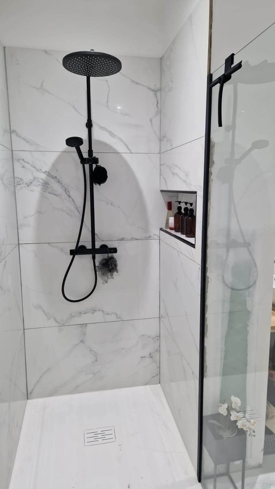 Une douche avec un carrelage blanc et noir