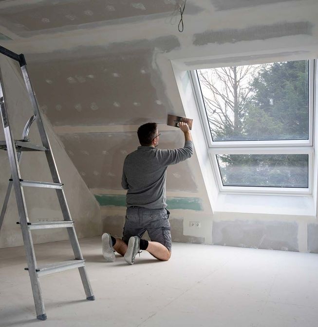 Un hombre está arrodillado en una habitación con una escalera.