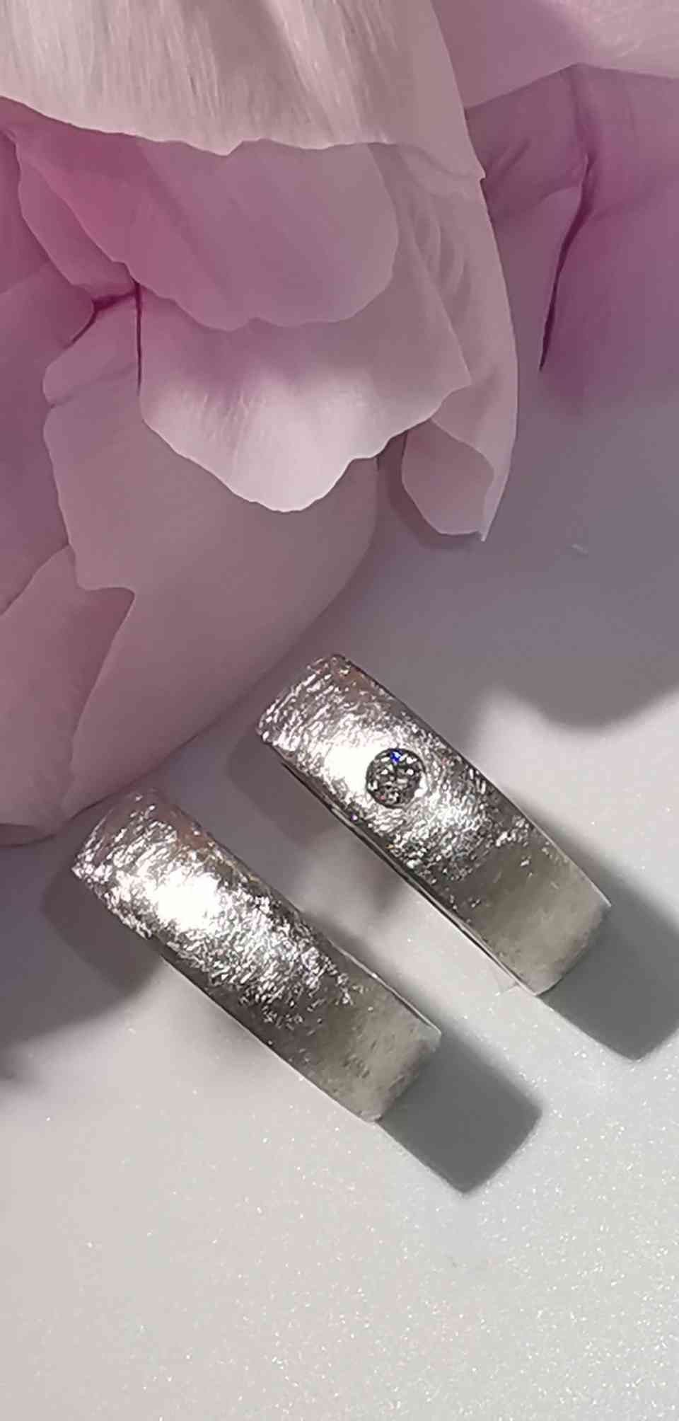 zwei Trauringe in Mattsilber, einer mit Diamant