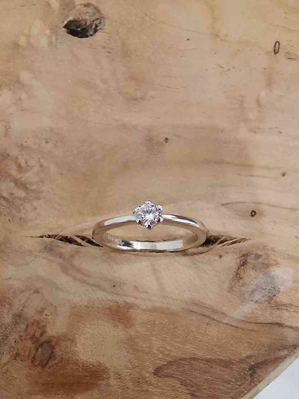 Verlobungsring mit einzelnem Diamanten auf Holzfläche