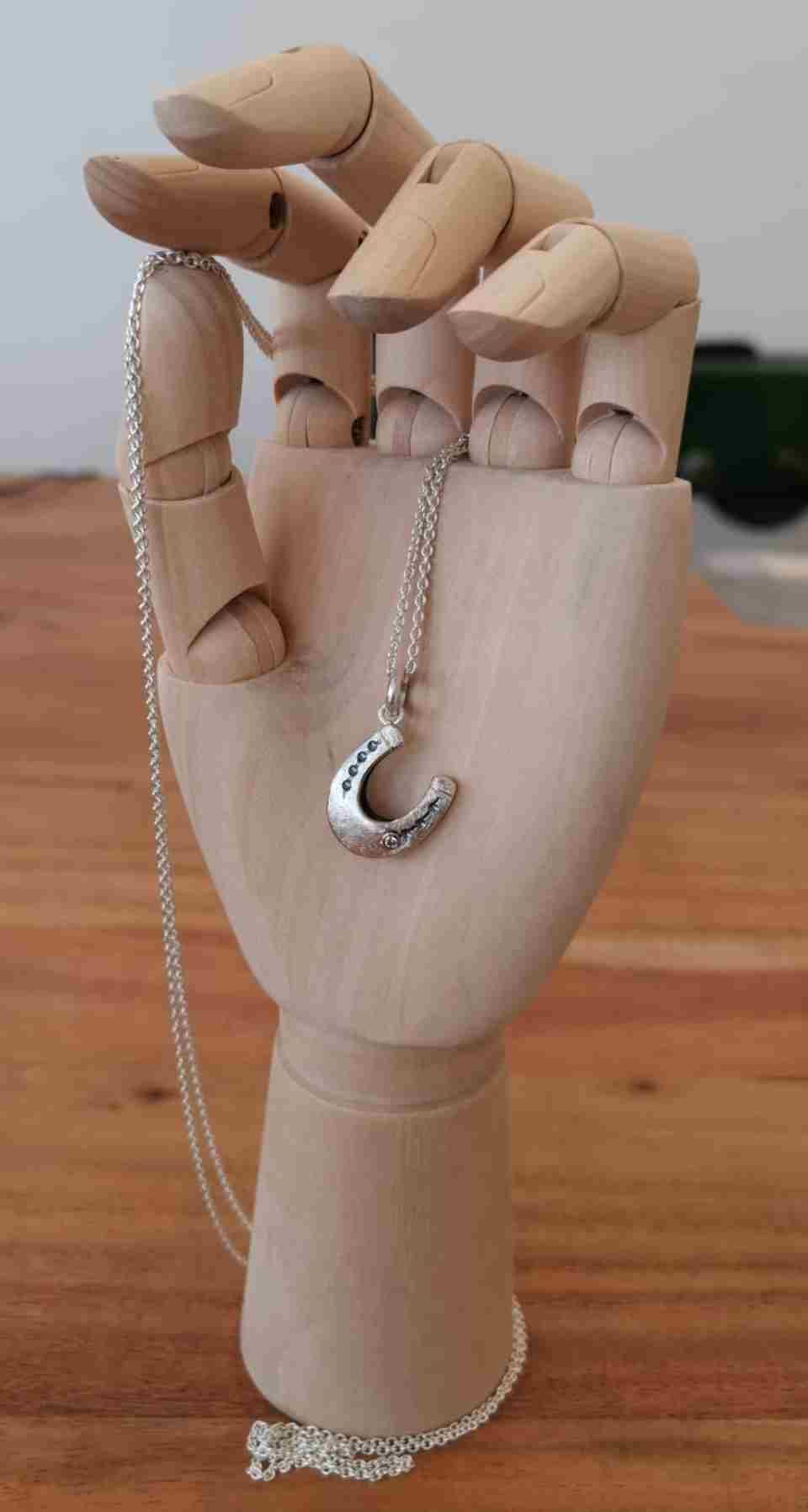 Schmuckhand hält Kette mit Anhänger