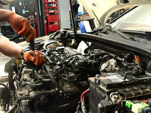 Un hombre está comprobando el aceite de un coche con una varilla de nivel.
