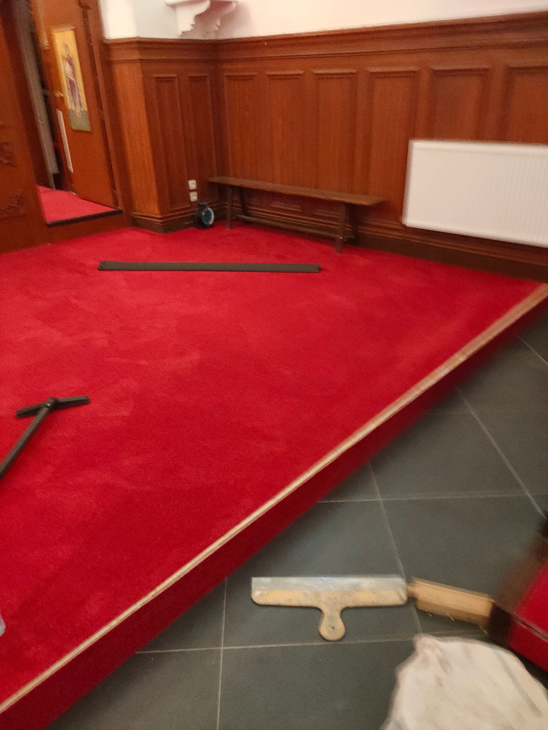 Une plateforme tapie de rouge dans une pièce éclairée - Entreprise Haikal