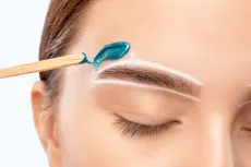 Una mujer se depila las cejas con un palito de madera.