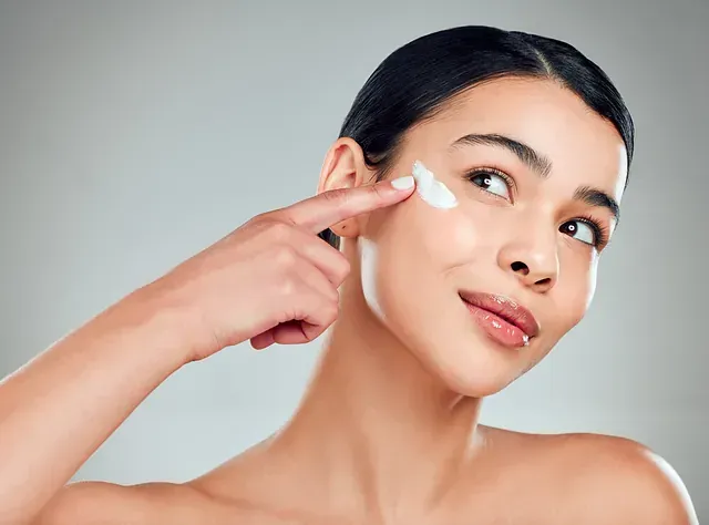 Una mujer se aplica crema en la cara.