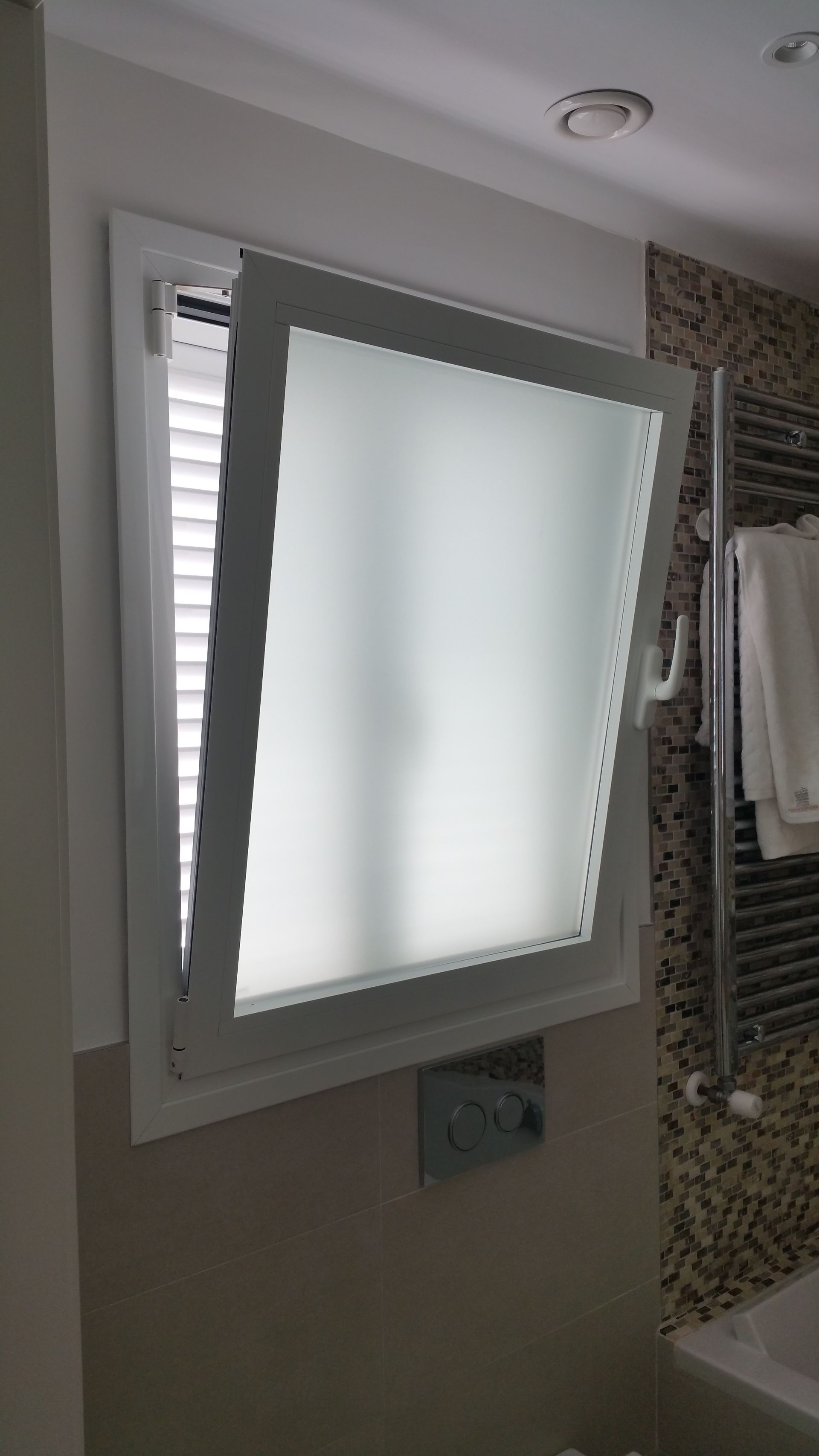 Un baño con ventana y toallero.