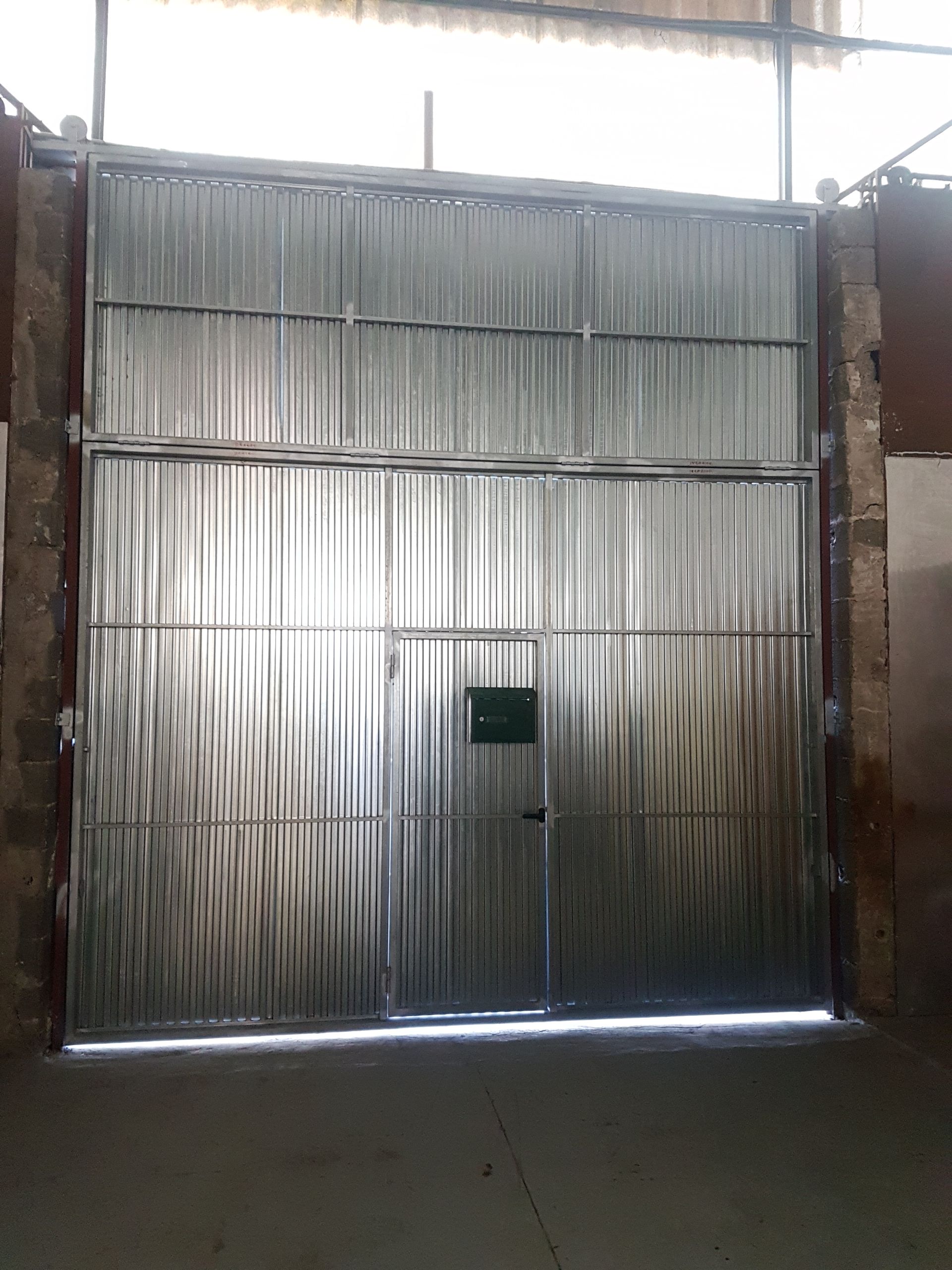 Una gran puerta de metal está abierta en un edificio.