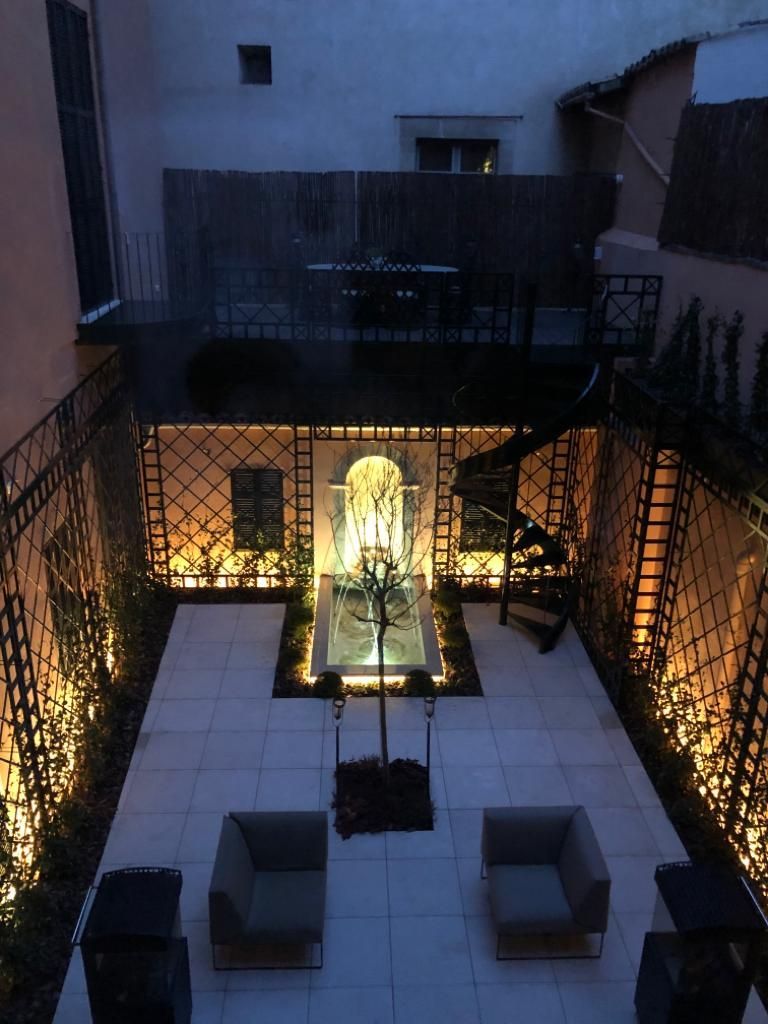 Un patio con sillas y una fuente por la noche.